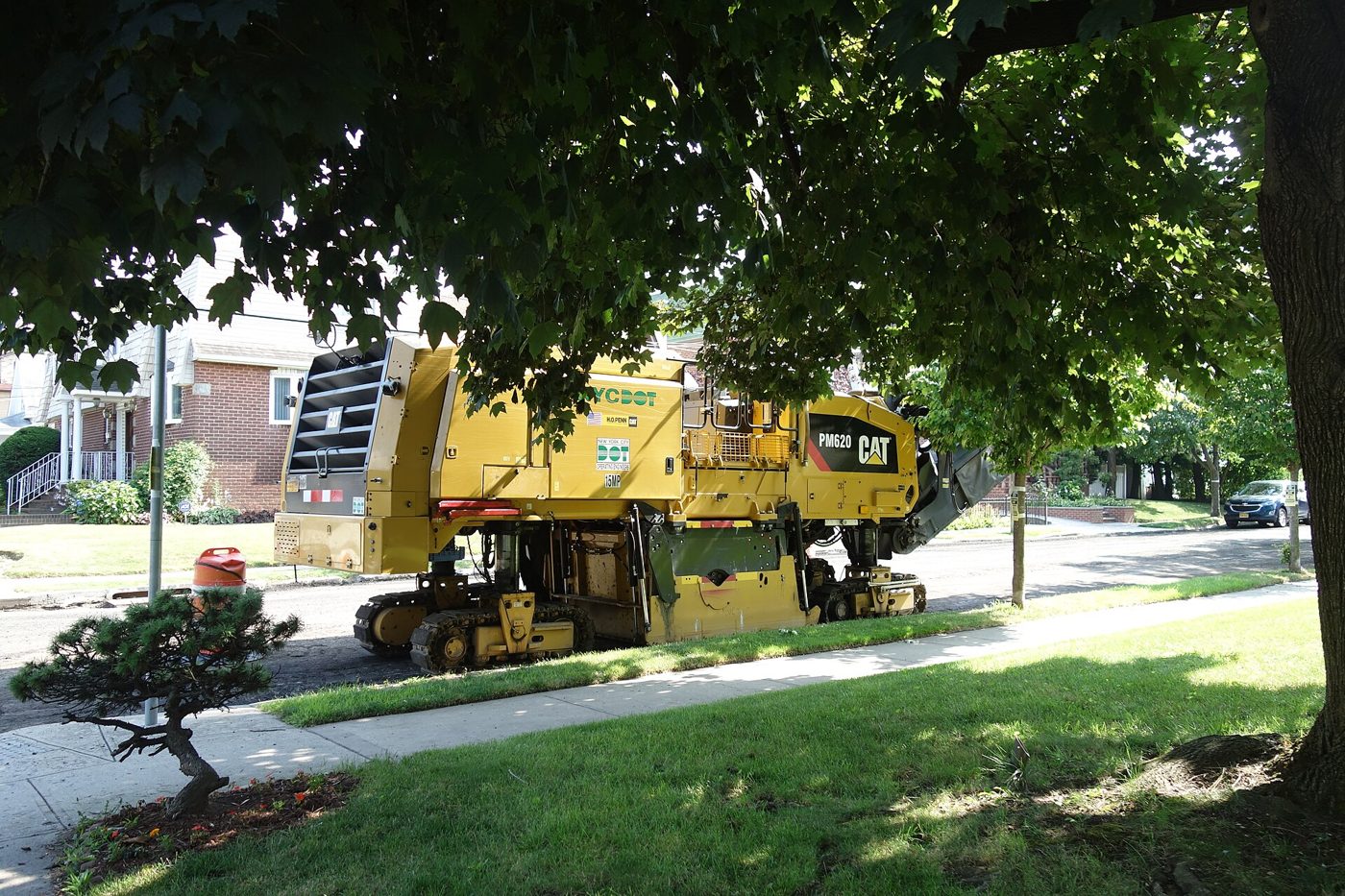 Asphalt paver and roller resurfacing a residential street.