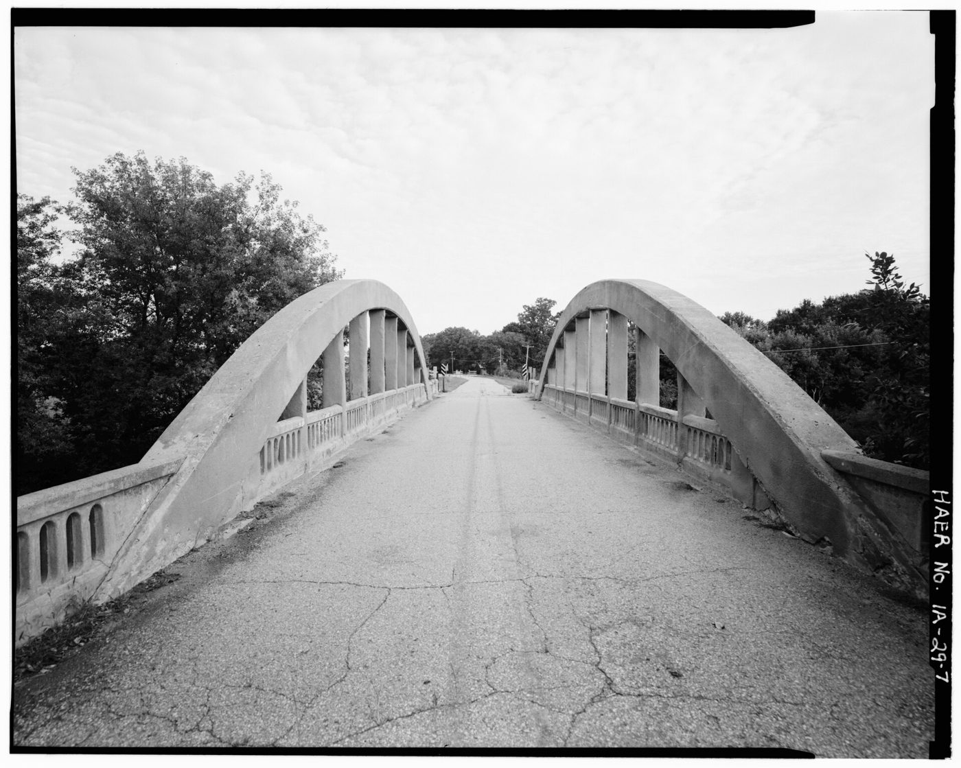 Concrete arch bridge deck and railings photographed along the roadway.