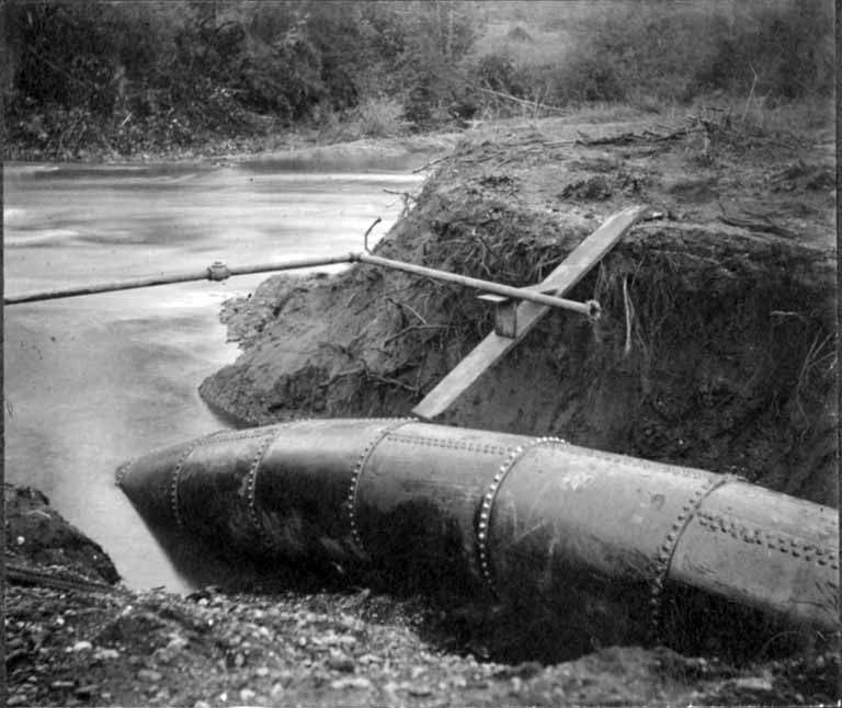 Large-diameter pipeline being lowered into an open trench.