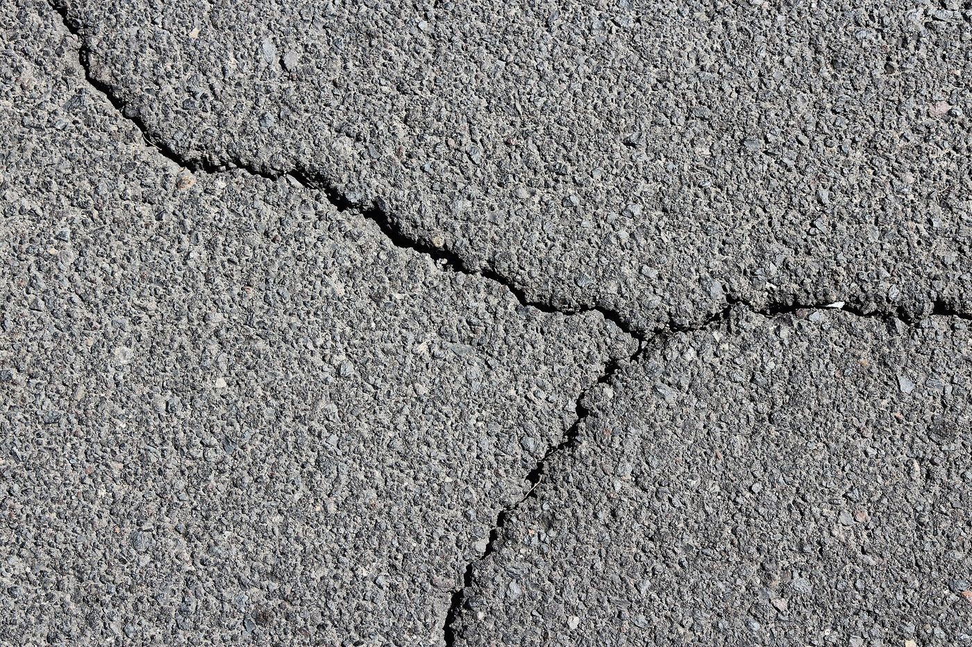 Close-up of interconnected cracks in an asphalt pavement surface.