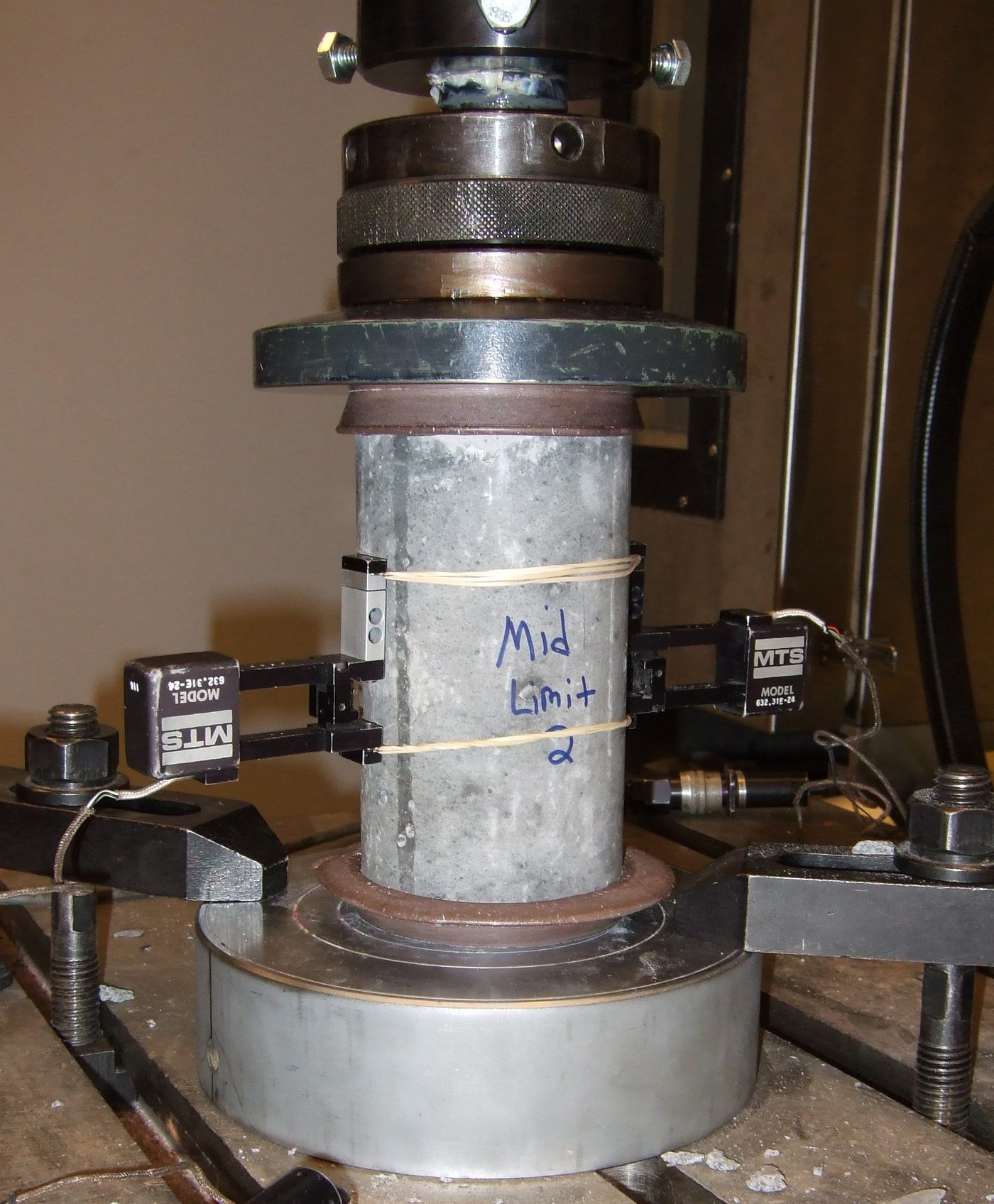 Concrete cylinder under axial load in a compression testing machine.