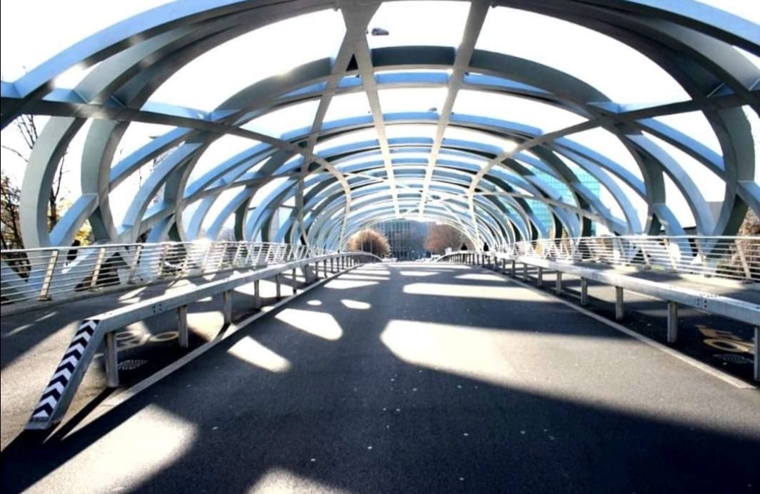 Interior of a steel and glass pedestrian bridge showing the structural framing.